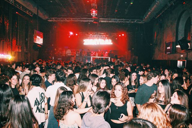 La multitud llena una sala amplia con una bola de espejos en el techo y el letrero de Zentral bajo luz roja al fondo; delante, varias chicas sonríen a cámara.