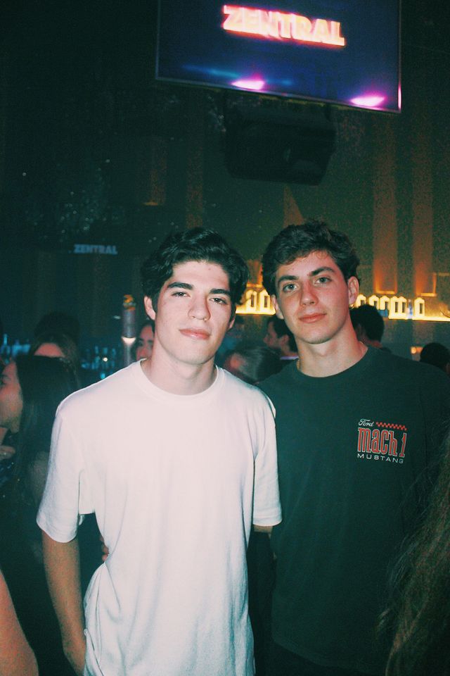 Dos chicos posan bajo una pantalla con el nombre de Zentral; el de camiseta blanca mira serio a cámara y el de camiseta oscura esboza una sonrisa.