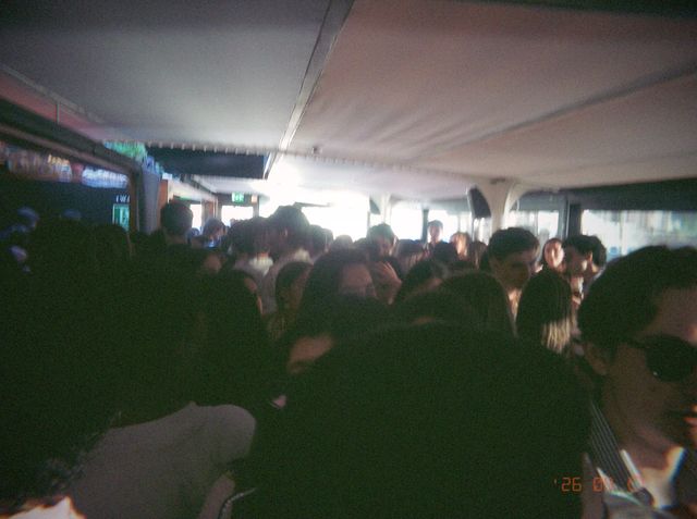 Una multitud abarrota la sala bajo el techo blanco, con los ventanales del fondo llenos de luz del día.