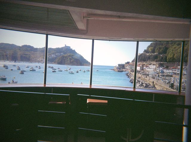 Los ventanales del local todavía vacío dan a la bahía llena de barcos, con el monte y el puerto al fondo.